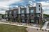 Modern three-story brick and stone townhomes with landscaped lawn at Erin Hills Estates