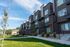 Brick townhomes at Erin Hills Estates with a green lawn, sidewalk, and landscaped entryways.