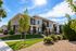 Two-story Erin Hills Estates townhomes with covered porches, green lawn, young trees, and a flowering rose garden.