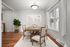 Elegant dining room with a chic wooden table set for six, accented by stylish decor, large window with soft natural light, and warm hardwood flooring.