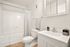 Bright and modern bathroom with pristine white fixtures, sleek vanity, and elegant ceramic tile flooring.