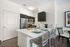 Modern kitchen with stainless steel appliances, sleek dark cabinets, and a bright breakfast bar setup with stylish seating.