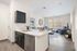 Modern open-concept living area with stylish kitchen island, cozy lounge space, and large sunlit windows.