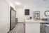 Contemporary kitchen with sleek stainless steel appliances, elegant countertops, and a view of a cozy living area adorned with modern decor.