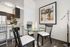 Contemporary dining area with a glass-top table, sleek black chairs, and elegant decor adjacent to a modern kitchen, perfect for cozy gatherings.