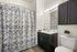 Elegant bathroom featuring stylish blue and white patterned shower curtain, modern vanity with sink, and chic dark cabinetry for a timeless look.