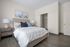 Inviting bedroom with a plush bed, soft pillows, stylish artwork, and a walk-in closet, offering a serene and modern living space.