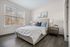 Inviting bedroom featuring a plush bed with cozy pillows, elegant artwork, and a large window with scenic woodland views.