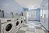 Bright and modern laundry room with multiple washing machines, vibrant blue walls, and checkered tile flooring, creating a fresh and inviting atmosphere.