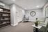 Elegant modern office space with cozy seating, lush greenery, a large decorative clock, and a well-organized bookshelf.