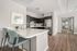 Modern kitchen with sleek dark cabinetry, stainless steel appliances, and elegant marble countertops. Open layout featuring cozy breakfast bar with plush seating, complemented by warm wooden flooring and stylish decor.