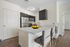 Modern kitchen with sleek stainless steel appliances, elegant dark cabinetry, and a stylish breakfast bar adorned with vibrant oranges.