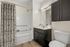 Modern bathroom design featuring elegant cabinetry, sleek countertop with sink, large mirror, and stylish bath and shower combo with a decorative curtain.