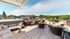 Luxurious outdoor terrace with modern seating, gourmet grills, and panoramic views of lush greenery and charming architecture.