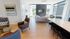Bright modern living area with sleek furnishings, large windows, and an elegant kitchen counter with bar stools.