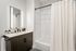 Modern bathroom featuring sleek vanity with dual sinks, elegant wooden cabinetry, and bright lighting.