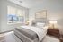 Inviting bedroom with a plush bed, elegant lamps, and a bright window view in a modern apartment.