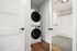 Modern apartment featuring an in-unit stacked washer and dryer set next to a contemporary bathroom with sleek tile flooring and bathtub.
