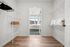 Bright walk-in closet leading to a cozy bedroom with large windows, featuring modern shelving and elegant wooden flooring.