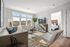 Chic living room with modern decor, featuring large windows, stylish furniture, and a cozy adjoining bedroom.