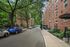 Charming street view with tree-lined walkways and classic brick apartment buildings, offering a serene urban living environment.
