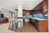 Sleek modern kitchen with rich wooden cabinetry, stainless steel appliances, blue tile backsplash, and stylish breakfast bar with chic seating.