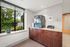 Bright and modern corner with a large window offering a serene garden view, accented by elegant cabinets and a sleek water dispenser.