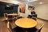 Modern communal dining area with elegant wooden tables, vibrant artwork, and an inviting coffee station.