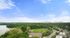 Breathtaking panoramic view of a vibrant cityscape with lush green parks, tennis courts, and a serene lake under a clear blue sky.