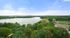 Breathtaking aerial view of lush greenery surrounding a serene lake, with sports courts providing recreational charm under a clear blue sky.