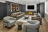 Luxurious modern living room with elegant gray sofas, sleek armchairs, and a cozy electric fireplace, bathed in natural light.