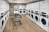 Modern laundry facility with rows of sleek washers and dryers, featuring bright lighting and convenient rolling baskets.