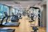 Modern fitness center with state-of-the-art exercise equipment, featuring treadmills, ellipticals, and strength machines, in a spacious, bright room with large windows.