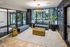 Chic apartment lobby with modern decor, featuring elegant gold accent tables, plush seating, and large windows with garden views.