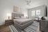 Modern bedroom featuring a chic upholstered bed, elegant nightstands with lamps, and a cozy armchair, bathed in natural light from a large window.