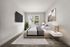 Modern bedroom with a cozy bed, stylish side tables, large flat-screen TV, and a window offering natural light and a view of greenery.