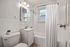 Bright and elegant bathroom with modern fixtures, featuring a sleek white vanity, bathtub, and charming natural light.