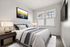 Bright and inviting bedroom with modern accents, featuring a comfortable bed, stylish artwork, and ample natural light through large windows.