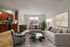 Elegant apartment living area with modern kitchen, cozy dining space, and stylishly furnished living room featuring chic artwork, lush plant, and abundant natural light.