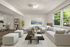 Inviting living room with plush gray sofas, chic decor, and large windows offering lush garden views, perfect for relaxation and entertainment.