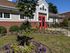 Charming apartment exterior with vibrant flower garden and inviting red door entrance.