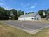 Community sports facility showcasing a pristine basketball court adjacent to a charming clubhouse, surrounded by lush greenery and blue skies.