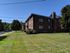 Charming brick apartment building in a serene setting with lush green lawns, perfect for enjoying peaceful living in a well-maintained community.
