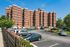 Charming brick apartment building with ample parking and lush greenery, perfect for comfortable urban living.