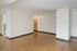 Spacious, modern apartment interior with warm wooden flooring, open layout, and a glimpse of a cozy kitchen.