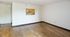 Bright and inviting open space with elegant wood flooring and a glimpse into a cozy kitchen area, perfect for modern living.
