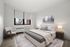 Bright and modern bedroom with elegant décor, featuring a cozy bed, stylish armchair, and large window with a serene view.