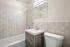Bright and modern bathroom with sleek fixtures, elegant tile backsplash, and a stylish vanity.