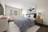 Bright and inviting bedroom featuring a plush bed with soft blue bedding, elegant nightstands, and large windows offering a scenic tree view.