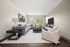 Inviting living room with a modern gray sectional sofa, stylish decor, and large windows offering natural light and serene views.